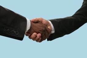 Two male hands shaking isolated on blue studio background Sign of joint plans for the future. Teamwork and communications. Two male hands shaking isolated on blue studio background. Concept of help, partnership, friendship, relation, business, togetherness.